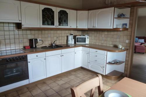een keuken met witte kasten, een wastafel en een fornuis bij Ferienwohnung Haus Handwerk in Duppach