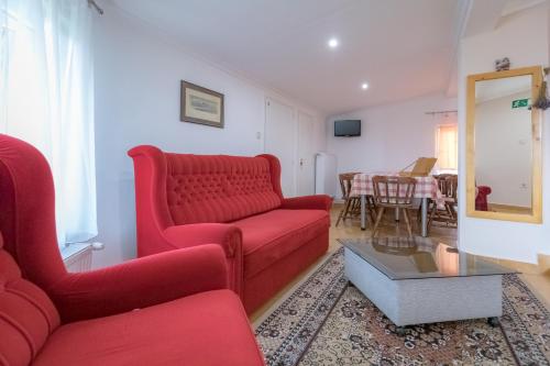 a living room with a red couch and a table at Orgona Vendégház in Murakeresztúr