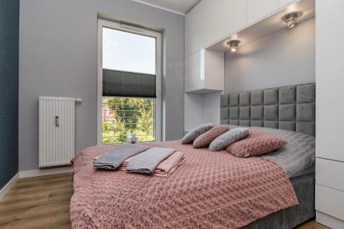 a bedroom with a large bed with pink pillows at Apartament36-1c Calamo Park in Olsztyn