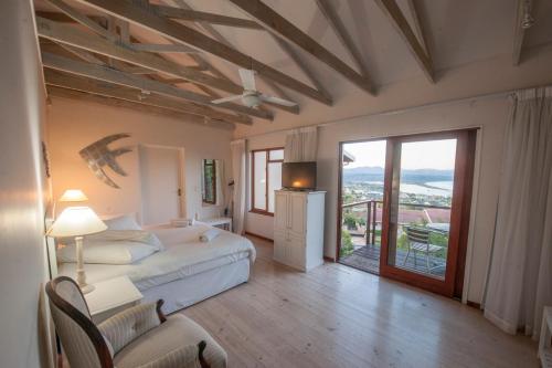 a large bedroom with a bed and a balcony at Panoramic Blue B&B in Plettenberg Bay