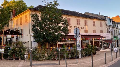 una calle en una ciudad con edificios y un árbol en Abelha Hôtel Le France en Brive-la-Gaillarde