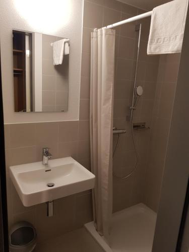 a bathroom with a sink and a shower with a mirror at Sport Resort Fiesch, Garni Goneri in Fiesch