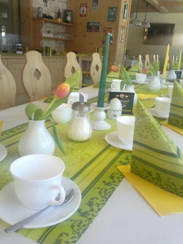 a table with white cups and saucers on it at Pension An der Erzgebirgsbahn in Kurort Oberwiesenthal