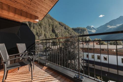 a balcony with chairs and a view of a train at Apart Peppone in Längenfeld