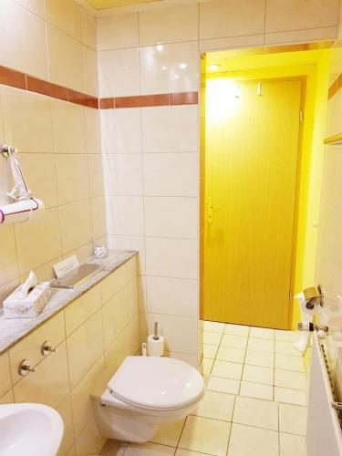 a bathroom with a toilet and a yellow door at Pension An der Erzgebirgsbahn in Kurort Oberwiesenthal