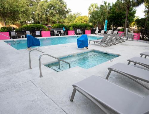 a swimming pool with chairs and a table at Aqua Beach Inn in Myrtle Beach