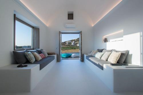 - un salon avec des canapés et une grande fenêtre dans l'établissement Luxury Santorini Villa Villa Pori Blanca Master Suite Private Pool and Stunning Sea View Near Pori Beach, à Foinikiá