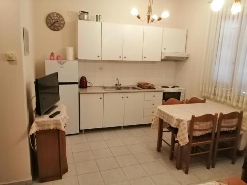a kitchen with white cabinets and a table and a television at BYT Village House in Áyios Khristóforos
