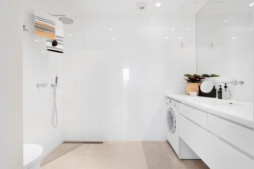 bagno bianco con lavandino e lavatrice di Seafront Penthouse Oslo a Oslo