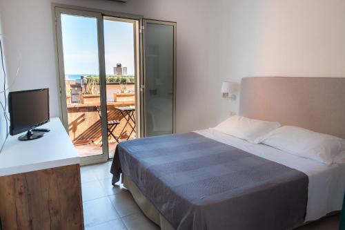 a bedroom with a bed and a television and a balcony at Hotel Villino Gallodoro in Taormina