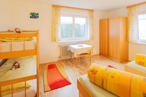 a small room with a bunk bed and a table at Berghof Vöglerbrand in Andelsbuch