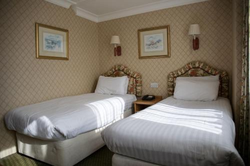 a hotel room with two beds and two pictures on the wall at Crown & Mitre Hotel in Carlisle