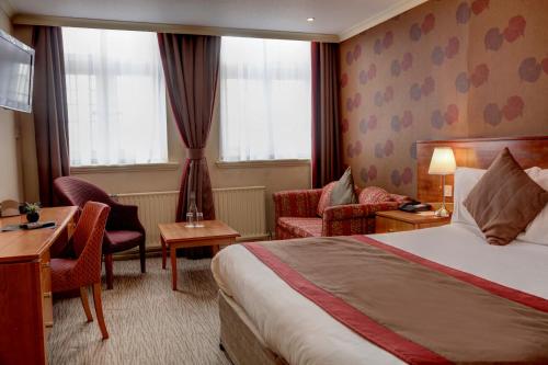 a hotel room with a bed and a desk and chairs at Crown & Mitre Hotel in Carlisle