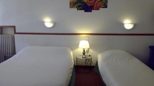 カルカソンヌにあるホテル サントラルのホテルルーム ベッド2台&ランプ付