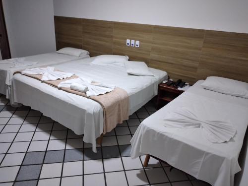 2 camas en una habitación de hotel con sábanas blancas en Arraial do Sol Beach Hotel, en Arraial d'Ajuda