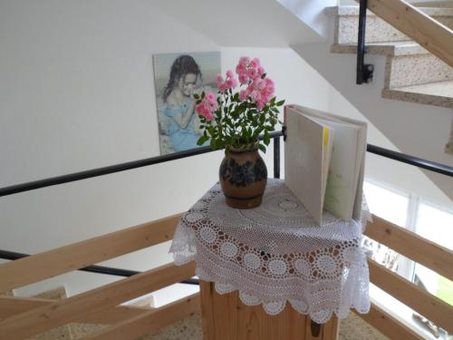 a table with a vase of flowers and a book at Berghof Vöglerbrand in Andelsbuch