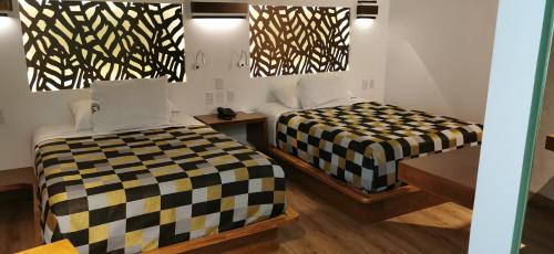 two beds in a room with black and white sheets at Hotel Lua in Mexico City