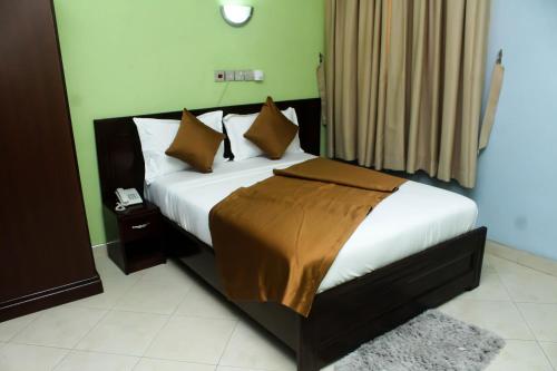 a bedroom with a bed with white sheets and brown pillows at SWEET PEE EXECUTIVE HOTEL in Ayeduasi