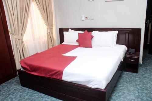 a bedroom with a large bed with red pillows at SWEET PEE EXECUTIVE HOTEL in Ayeduasi