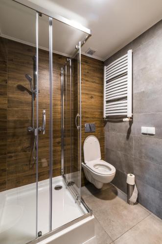 a bathroom with a toilet and a glass shower stall at Apartamenty Medyka Park in Medyka