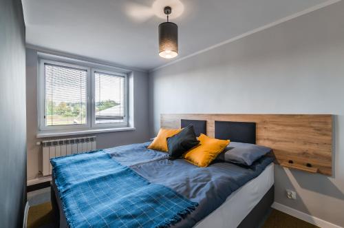 a bedroom with a bed with blue and yellow pillows at Apartamenty Medyka Park in Medyka