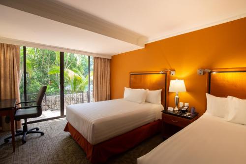 Habitación de hotel con 2 camas, escritorio y ventana en HS HOTSSON Hotel Tampico, en Tampico