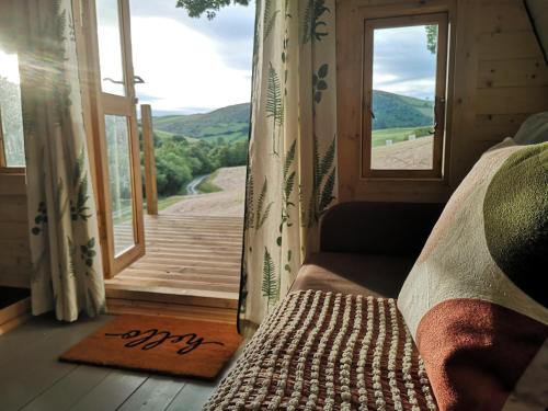 a room with a door and a window with a view at Tan-y-Dderwen Pod in Machynlleth