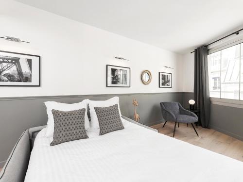 une chambre avec un grand lit blanc et une chaise dans l'établissement LivinParis - Luxury 3 Bedrooms Le Marais III, à Paris