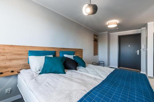 a bedroom with a large bed with blue pillows at Apartamenty Medyka Park in Medyka