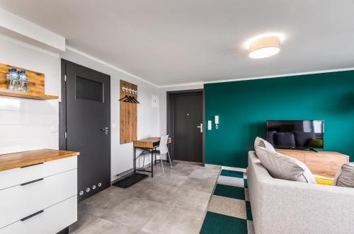 a living room with a couch and a green wall at Apartamenty Medyka Park in Medyka