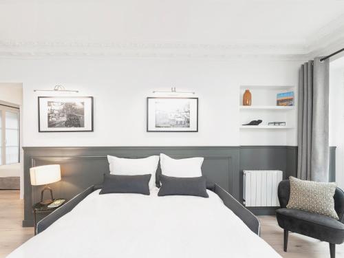 une chambre avec un grand lit blanc et une chaise dans l'établissement LivinParis - Luxury 3 Bedrooms Le Louvre II, à Paris