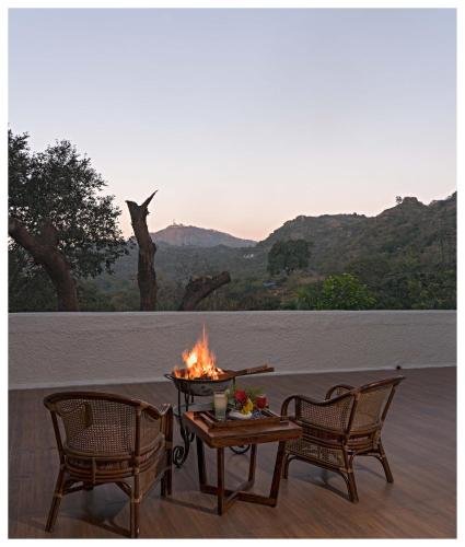 a fire pit sitting on a deck with two chairs at Wordsworth Lodge in Mount Ābu
