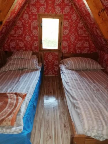 2 łóżka w małym pokoju z czerwonymi ścianami w obiekcie Fábián Apartman w mieście Tata