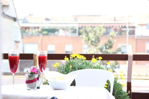 ミラノにあるホテル ルガノのバルコニーにテーブルとワイン2杯
