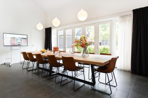 a dining room with a large wooden table and chairs at Bed & Breakfast De Oude Kapel in Driebergen