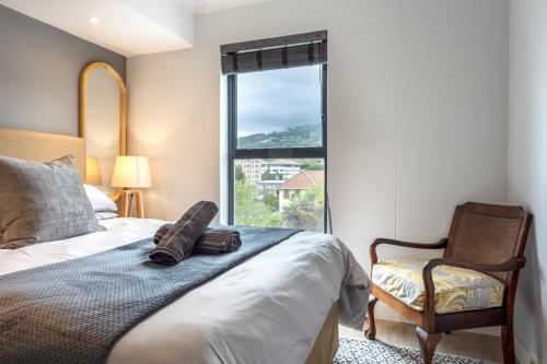 1 dormitorio con 1 cama, 1 silla y 1 ventana en BERGSIG Spacious Deluxe Corner Unit, en Ciudad del Cabo