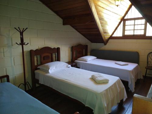 1 dormitorio con 2 camas y ventana en Chale da Ana, en Santo Antônio do Pinhal