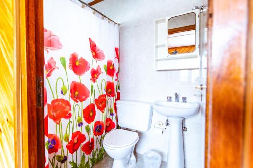 a bathroom with a toilet and a flower shower curtain at Bla Guest House in El Calafate
