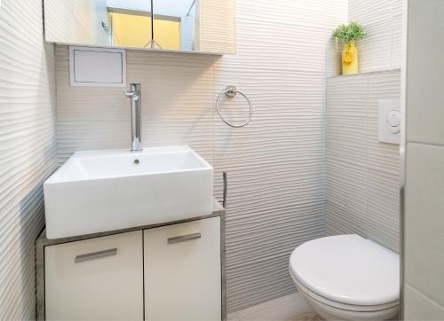 uma casa de banho com um lavatório branco e um WC. em Apartment Tomas em Split