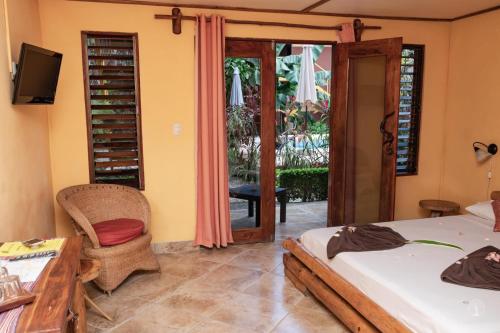 um quarto com 2 camas, uma mesa e um pátio em Samara Palm Lodge em Sámara