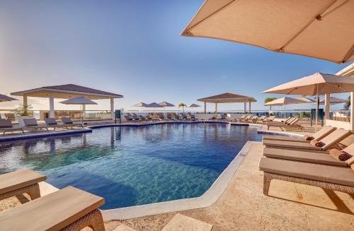 einen Pool mit Stühlen und Sonnenschirmen in einem Resort in der Unterkunft Royalton Grenada, An Autograph Collection All-Inclusive Resort in Bamboo