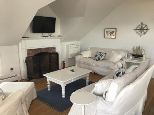 a living room with white furniture and a fireplace at Love Sand, Madaket on the Beach in Nantucket