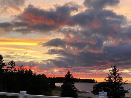 a sunset over a body of water with clouds at The Purple Martin Lakeside Inn Bird Sanctuary on Lake Huron in Rogers City