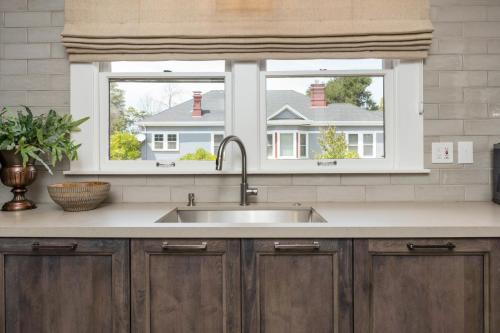 a kitchen with a sink and two windows at The Main Street House - Designer Napa Home in Napa