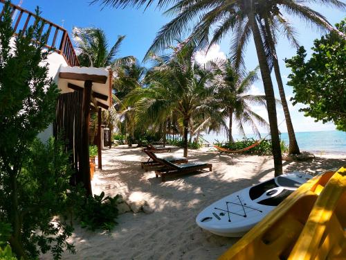 a surfboard sitting on a beach with palm trees at Casa Colibrí Tankah in Tulum