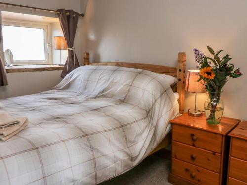 ein Schlafzimmer mit einem Bett und einer Blumenvase auf einem Nachttisch in der Unterkunft Wren in Scarborough