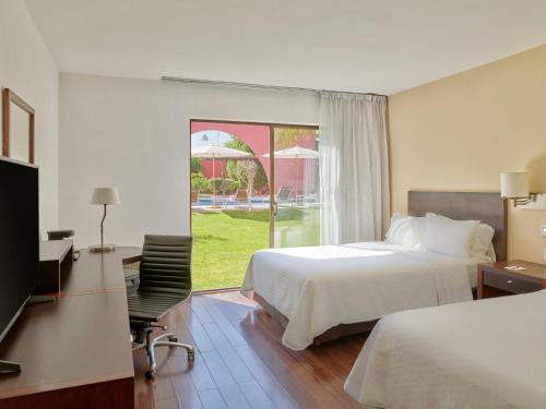 Habitación de hotel con cama y ventana en Fiesta Inn Aguascalientes, en Aguascalientes