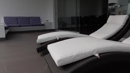 two white beds in a room with a couch at Donde Lalo in Asia