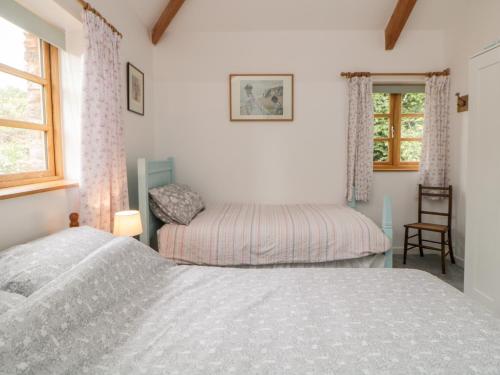 a bedroom with two beds and a chair and a window at The Old Haybarn in Newton Abbot