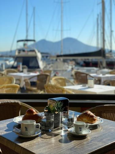 a table with coffee cups and pastries on a table with a harbor at Transatlantico in Naples